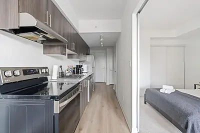 a small kitchen with a sink and a bed in a room at Scarborough Oasis near UofT campus, Free Parking in Toronto
