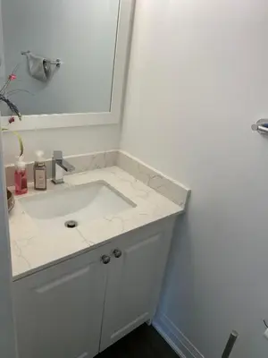 a white bathroom with a sink and a mirror at The cozy crest in Brampton