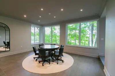 a dining room with a table and chairs and windows at Luxury 4BR Stay with Swim Spa, Golf and Fireplaces in Caledon