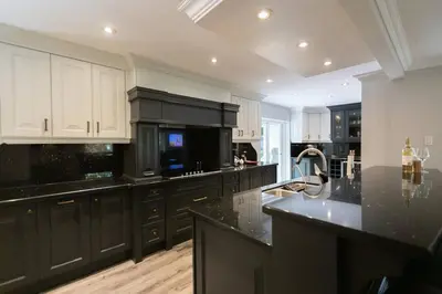 a large kitchen with black cabinets and black counter tops at Luxury 4BR Stay with Swim Spa, Golf and Fireplaces in Caledon