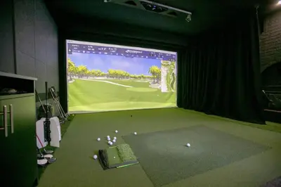 a room with a screen with golf balls on the floor at Luxury 4BR Stay with Swim Spa, Golf and Fireplaces in Caledon