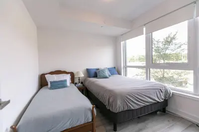 two beds in a room with a window at Modern 2BR Getaway with Balcony, BBQ and Parking in Innisfil