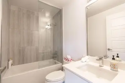 a bathroom with a tub and a toilet and a sink at Modern 2BR Getaway with Balcony, BBQ and Parking in Innisfil