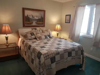 a bedroom with a bed and two lamps on tables at White Rolling Sands of Penetang by Theatre in Penetanguishene