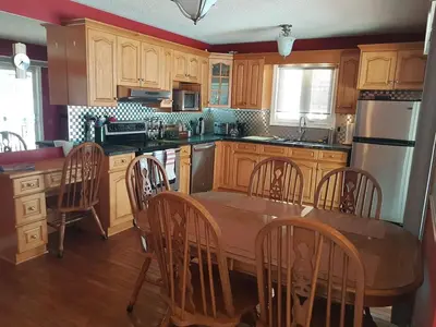 a kitchen with wooden cabinets and a table and chairs at White Rolling Sands of Penetang by Theatre in Penetanguishene