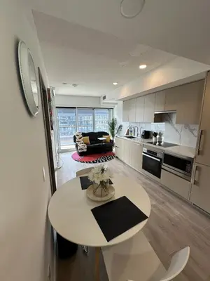 a kitchen and living room with a table in the middle at Entire Luxe Condo in Downtown Toronto in Toronto