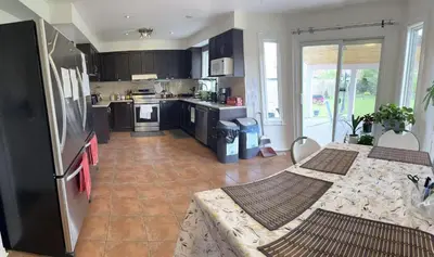a kitchen with black cabinets and a table with chairs at VP1 master bedroom on second floor in Mississauga