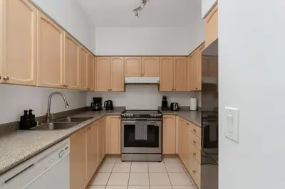 a kitchen with wooden cabinets and a stove top oven at Stunning 1BD Lakeview Condo near BMO Free Parking in Toronto