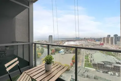 a balcony with a wooden bench and a view of a city at Stunning 1BD Lakeview Condo near BMO Free Parking in Toronto
