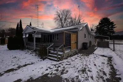 a small house in the snow with a sunset at Lake-Access Cottage- Hot Tub, Fireplace&Pool Table in Bewdley
