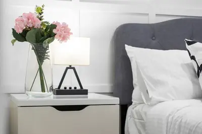 a bed with a table with a vase of flowers on it at High Park Grove Modern 1B1B, Kitchen, Laundry in Toronto