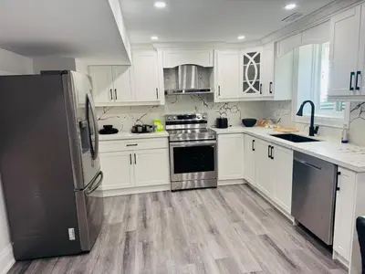 a kitchen with white cabinets and stainless steel appliances at Hearth & Home Spacious Suite in Pickering