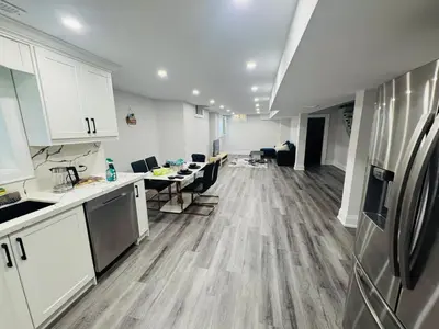 an empty kitchen with white cabinets and a refrigerator at Hearth & Home Spacious Suite in Pickering