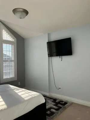 a bedroom with a bed and a flat screen tv on the wall at 3300 SqFt - Modern and Comfort - 3 BDRM Getaway - Relax - Unwind - Explore - Near Toronto Pearson Airport & Toronto Downtown in Brampton