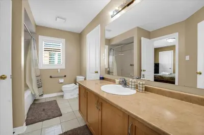 a bathroom with a sink and a toilet and a mirror at Luxury Mansion by Toronto and YYZ with Large Backyard Weddings in Brampton