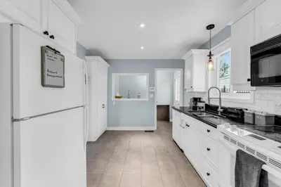 a white kitchen with a sink and a refrigerator at Bright 6BR Near Niagara Falls with BBQ Yard in Thorold