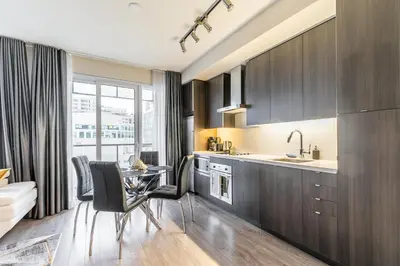 a kitchen with dark wood cabinets and a table and chairs at Modern 1 Bedroom Condo Front Street Downtown Toronto in Toronto