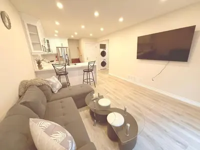 a living room with a couch and a tv and a kitchen at Modern 1-BR Suite EV Charger, Backyard BBQ & Near Square One in Mississauga