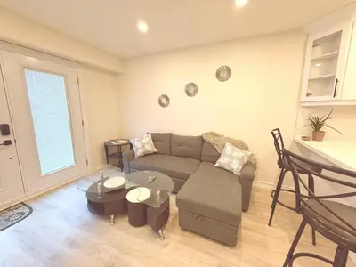 a living room with a couch and a table at Modern 1-BR Suite EV Charger, Backyard BBQ & Near Square One in Mississauga