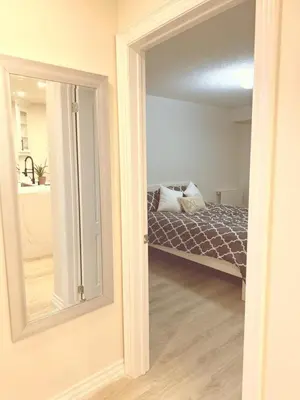 a bedroom with a bed and a mirror at Modern 1-BR Suite EV Charger, Backyard BBQ & Near Square One in Mississauga