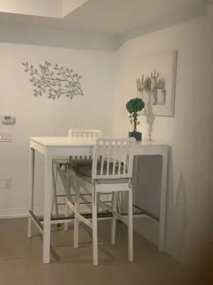 a white dining room table with two chairs and a plant at Luxury All-Inclusive One-Bedroom Condo in Downtown in Toronto
