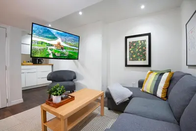 a living room with a couch and a tv on the wall at East Toronto BNB in Toronto