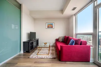 a living room with a red couch and a tv at High Floor 1 Bedroom plus Den Condo Apartment City View North York Toronto in Toronto