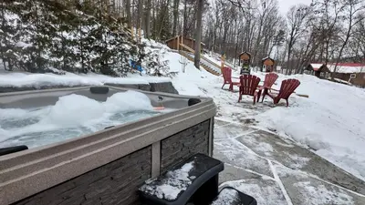 a hot tub with chairs and snow in a yard at Winter at Wildwood in Bailieboro
