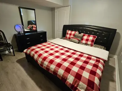 a bed with a checkered blanket and a mirror at Peace Apartment in Brampton