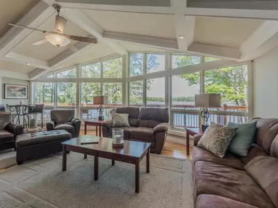 a living room with couches and a table at Private Lakefront Cottage Living on Muldrew Lake in Gravenhurst
