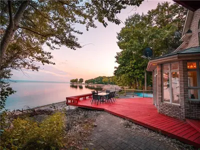 a house with a red deck next to the water at Lakeside Villa across Whisky Run Golf Club in Port Colborne