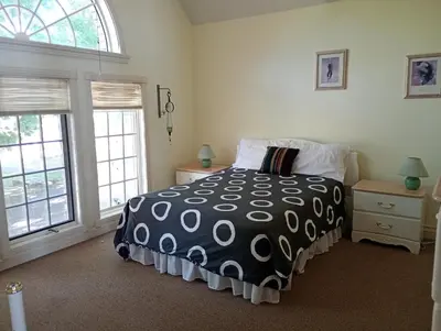 a bedroom with a black and white bed and windows at Lakeside Villa across Whisky Run Golf Club in Port Colborne