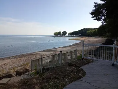 a beach with a fence next to the water at Lakeside Villa across Whisky Run Golf Club in Port Colborne