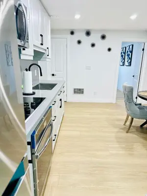 a kitchen with white cabinets and a sink and a table at Modern 2BR suite Kitchen Workspace Laundry in London