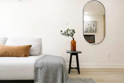 a living room with a bed and a round mirror at The Ember Suite in Peterborough