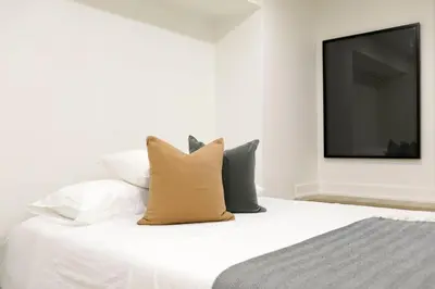 a white bed with pillows and a television on a wall at The Ember Suite in Peterborough