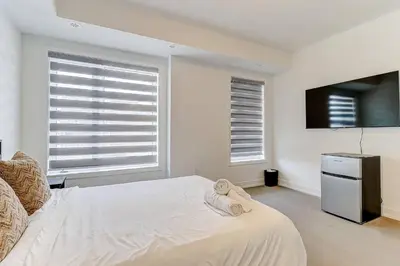 a white bedroom with a bed and a television at Downsview Park Luxury Townhome near Yorkdale Transit in Toronto
