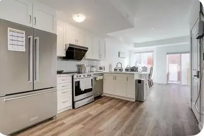 a large kitchen with white appliances and wooden floors at Downsview Park Luxury Townhome near Yorkdale Transit in Toronto