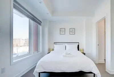 a white bedroom with a large bed and a window at Downsview Park Luxury Townhome near Yorkdale Transit in Toronto
