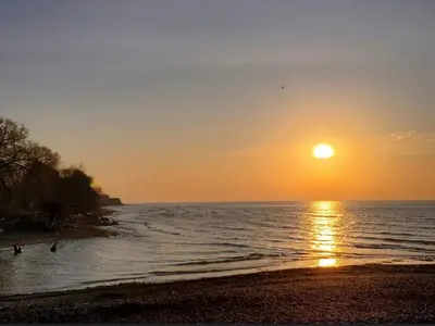 a sunset on a beach with the sun setting at Beautiful Lake Side Neighbourhood Home in Ajax, ON in Ajax