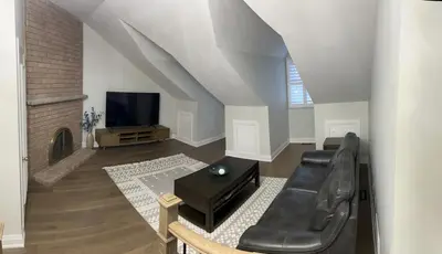 a living room with a black leather couch and a tv at Beautiful Lake Side Neighbourhood Home in Ajax, ON in Ajax
