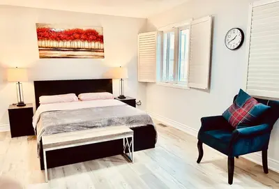 a bedroom with a bed and a chair and a clock at House of 3 Bed 3 Wash-Crib-King Bed-85' TV-Wrkspce in Oakville