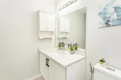 a white bathroom with a sink and a mirror at House of 3 Bed 3 Wash-Crib-King Bed-85' TV-Wrkspce in Oakville