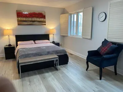 a bedroom with a bed and a chair and a clock at House of 3 Bed 3 Wash-Crib-King Bed-85' TV-Wrkspce in Oakville