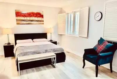 a bedroom with a bed and a chair and a clock at House of 3 Bed 3 Wash-Crib-King Bed-85' TV-Wrkspce in Oakville