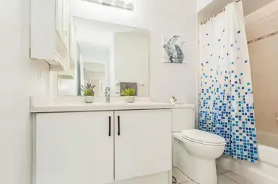 a bathroom with a toilet and a sink and a mirror at House of 3 Bed 3 Wash-Crib-King Bed-85' TV-Wrkspce in Oakville