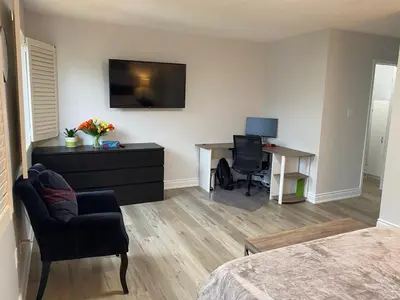 a room with a bedroom with a desk and a television at House of 3 Bed 3 Wash-Crib-King Bed-85' TV-Wrkspce in Oakville