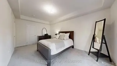 a white bedroom with a bed and a mirror at Modern in Richmond Hill in Richmond Hill