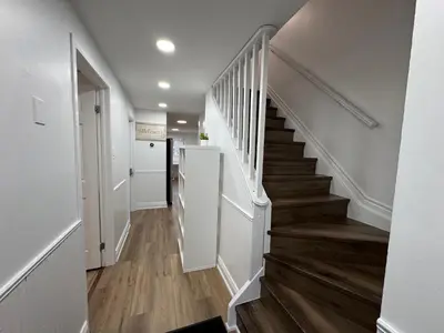 a hallway with a staircase with white walls and wood floors at North Barrie !A Stylish and Spacious Private Bedroom with Private Bathroom in Barrie