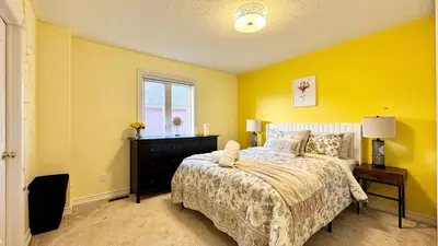 a bedroom with yellow walls and a bed and a window at Designer 4BR Retreat, Luxe Living & Family-Friendly Fun in Mississauga